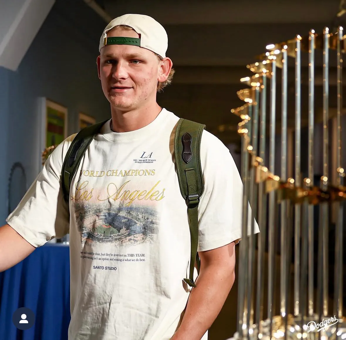 Emmet in a World Champions Los Angeles cream colour shirt and matching hat.
The khaki strap on his hat matches his backpack straps. He clearly does not own an iron. 